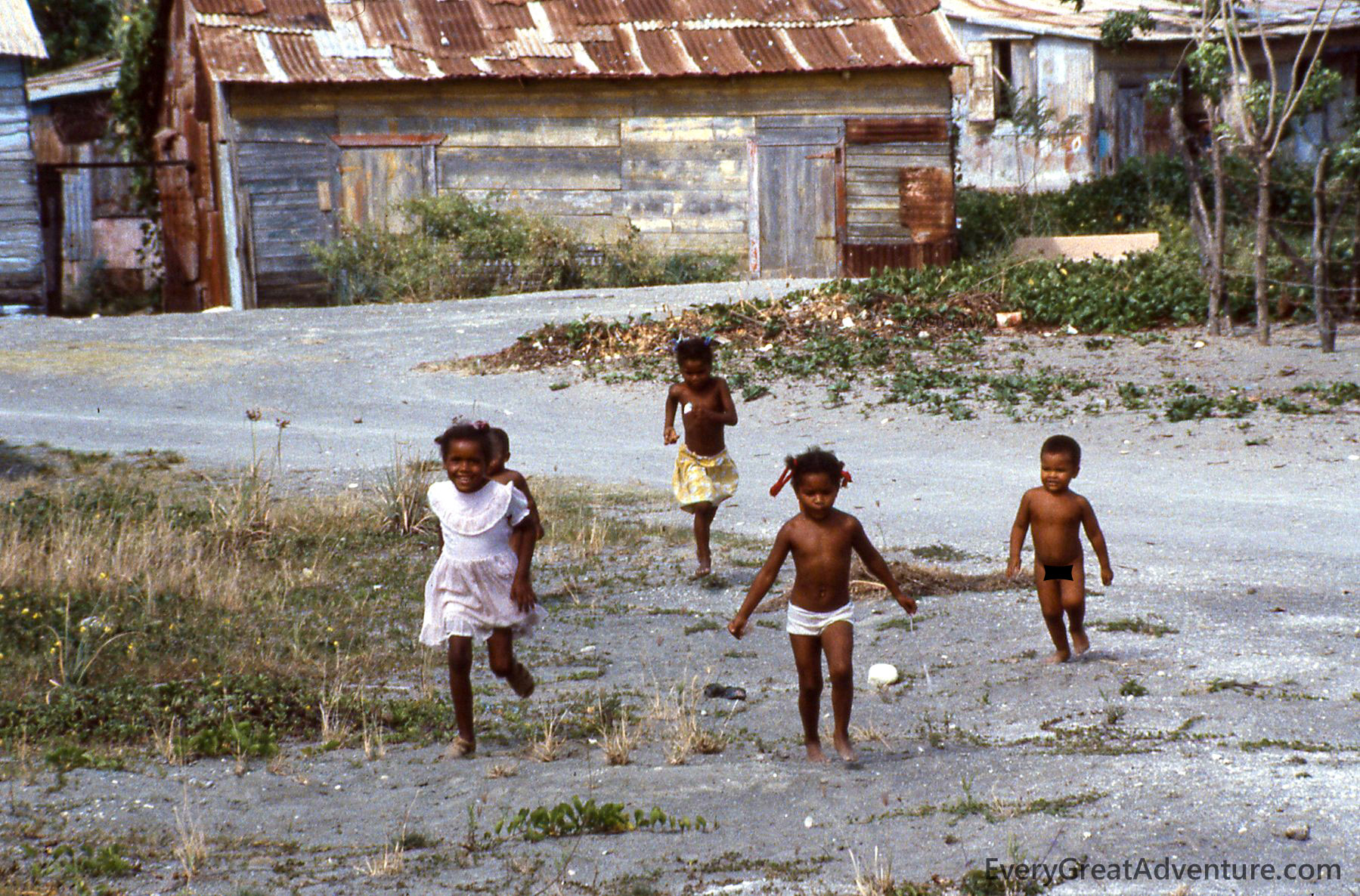 Children of Haiti, running toward photographer, through dirt, wearing few clothes