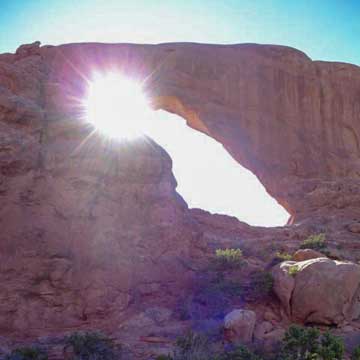 sun shining through upper corner of natural arch formation in Arches National Park