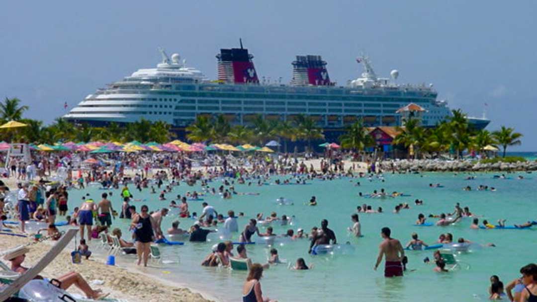 Disney Cruise Line ship at Disney's private Island Castaway Cay showing lots of people in the water and on the beach nearby