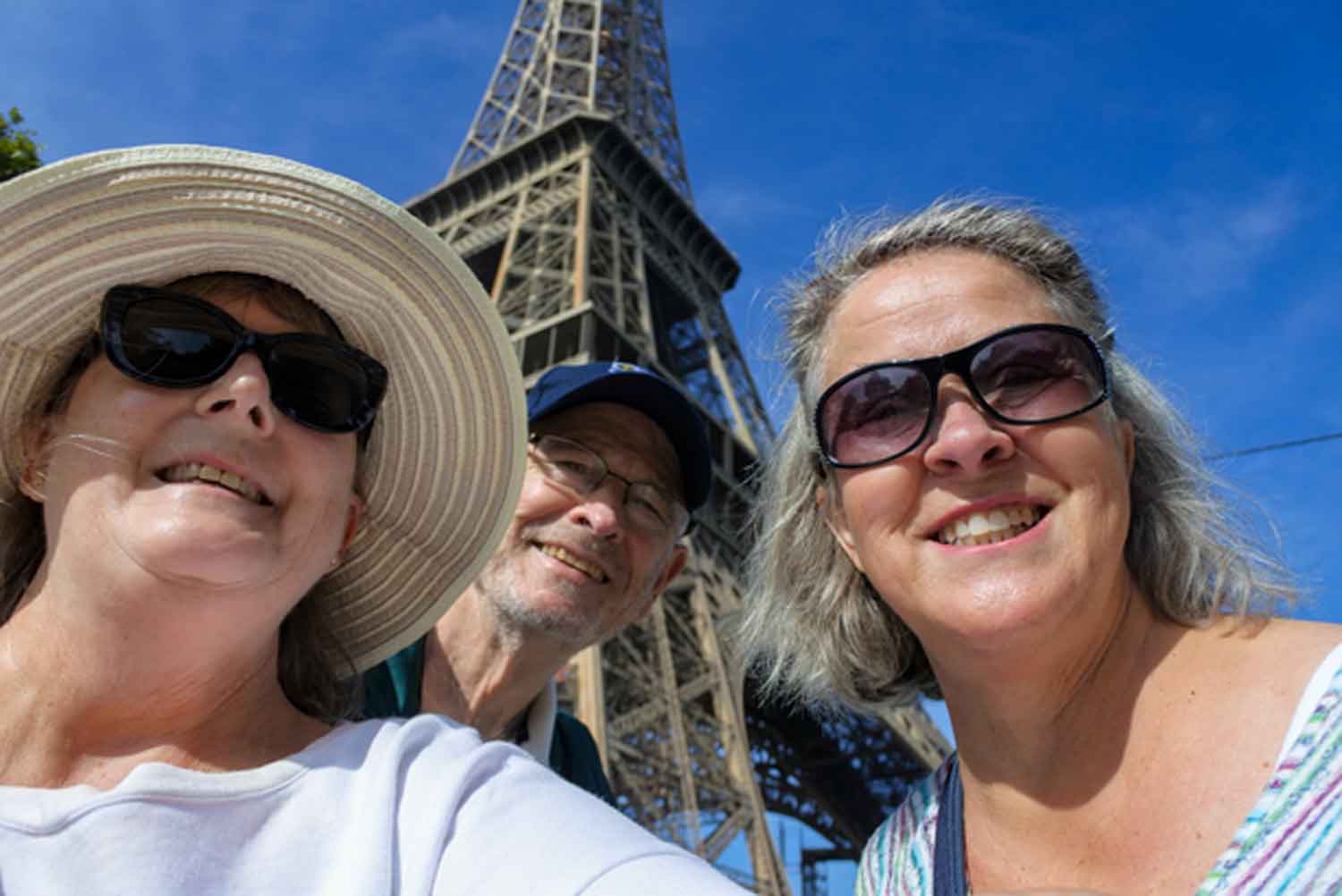 two women and a man in selfie with Eiffel Tower in the background