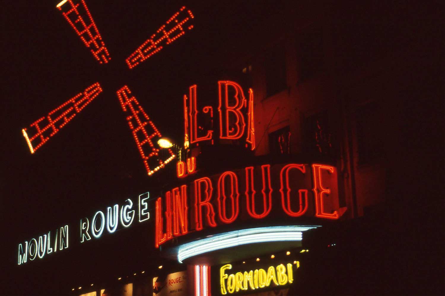Red neon signage depicting windmill blades at the famous Moulin Rouge