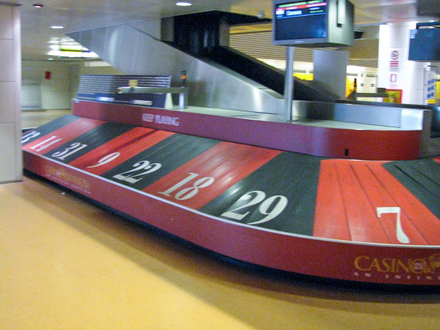 Empty luggage carousel that is painted with red and black sections, each numbered in the manner of a roulette wheel. Seen in Venice Italy