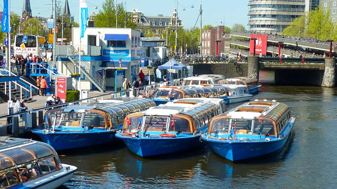 photo of blue boats with clear glass tops (canal tourist boats) tied up at the dock