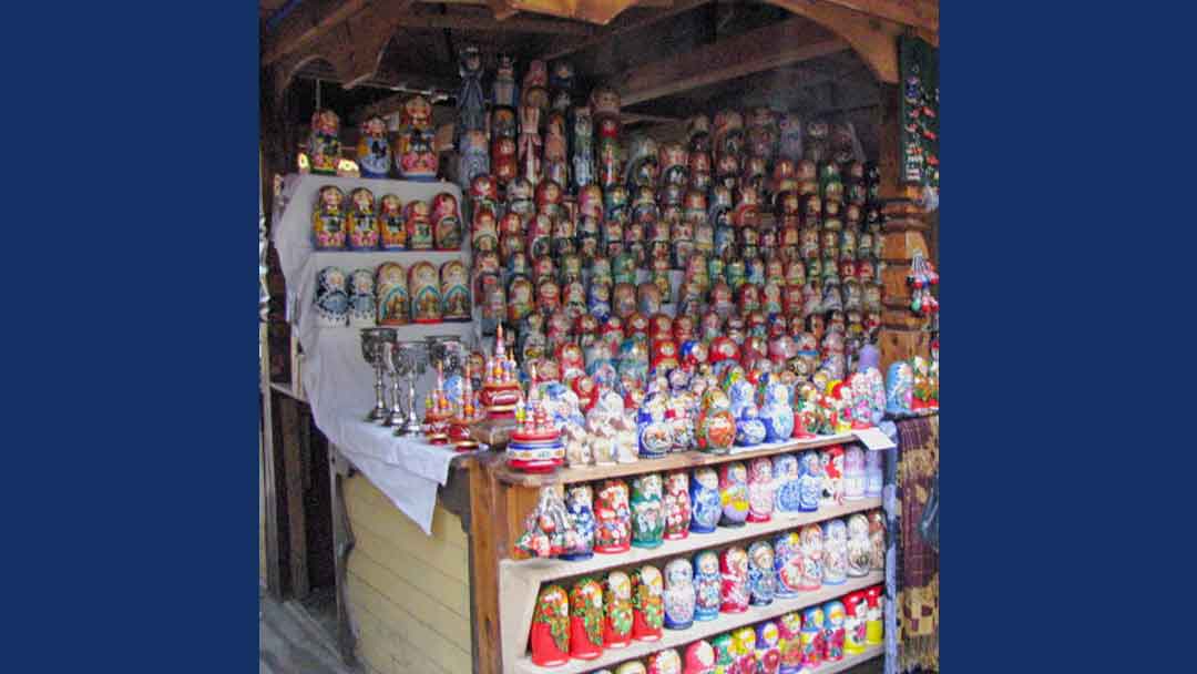 row upon row of wood stacking dolls in a variety of designs set up on shelves in flea market stall
