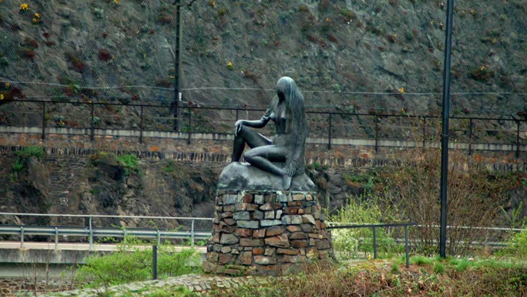 Statue along the Rhine River of woman with long hair flowing over her shoulders sitting on a rock