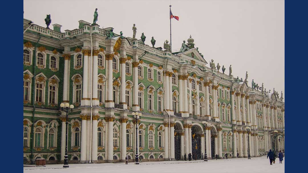 Exterior of building. Green walls. White pillars and window frames. Gold trim on pillars and window frames. Statues on tope of building. Russian flag flying over building.
