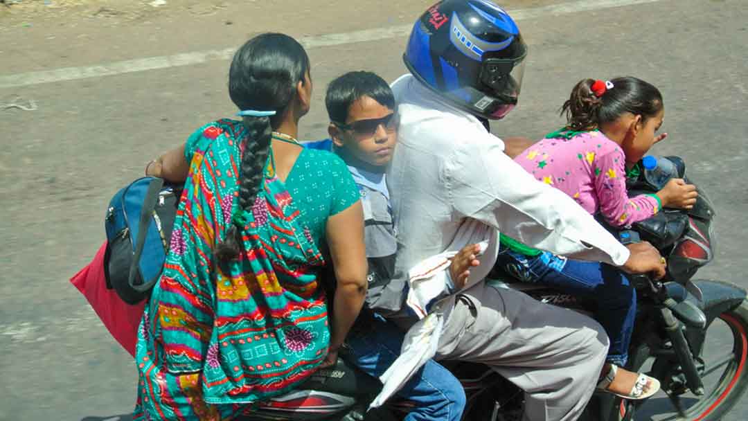 Family of four riding on one motorcycle, only father is wearing helmet