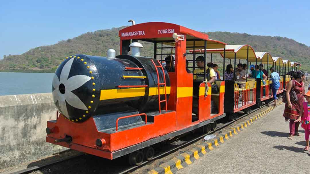 Orange small train which takes tourists from the pier to the base of the hill on Elephanta Island