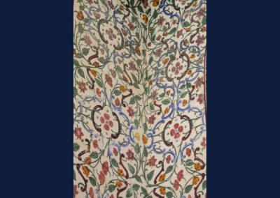 Elaborately painted walls in a floral decoration using green, yellow, red, and blue on a beige background.