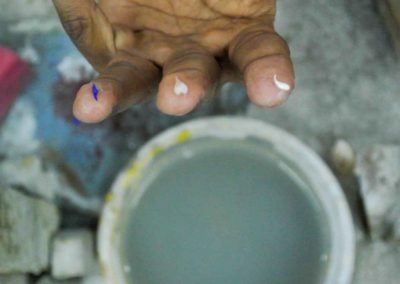 Hand showing three fingers. On tips of each finger is a very small ground and shaped piece of semi-precious stone to be used for inlay.