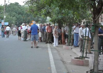 Numerous people standing in a queue in the early morning light.