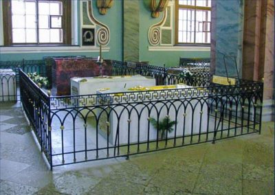 interior of church with multiple tombs in an area enclosed by a black wrought iron fence