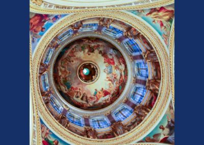Interior of dome of cathedral showing elaborate paintings, lit by windows within the dome.