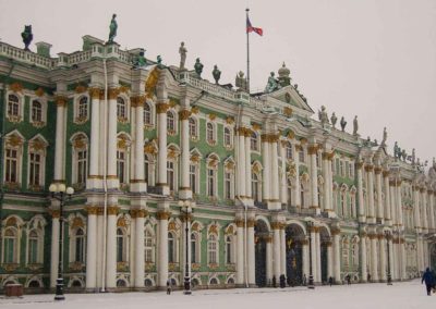 Exterior of building. Green walls. White pillars and window frames. Gold trim on pillars and window frames. Statues on tope of building. Russian flag flying over building.