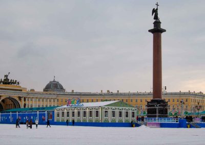 Large palace in background, tall monolith in foreground. Around monolith is an ice skating rink and a temporary shelter for skaters.
