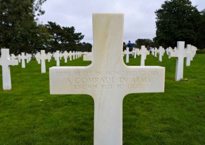 One of many white crosses in a cemetery bearing the inscription Here rests in honored glory a comrade in arms known but to God