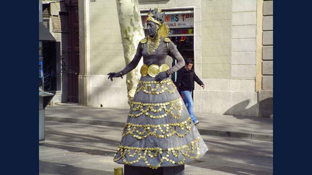 Photo of a woman dressed in gray and gold, pretending to be a statue on the street.