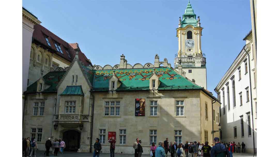 Old town hall of Bratislava with green tiled roof and large clock tower.