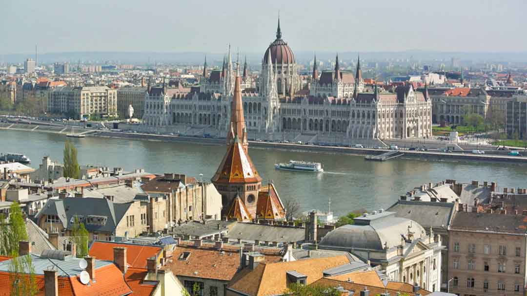 Overlooking Danube River from atop a hill. Large white building with red roof (Parliament) is on opposite side of the river.