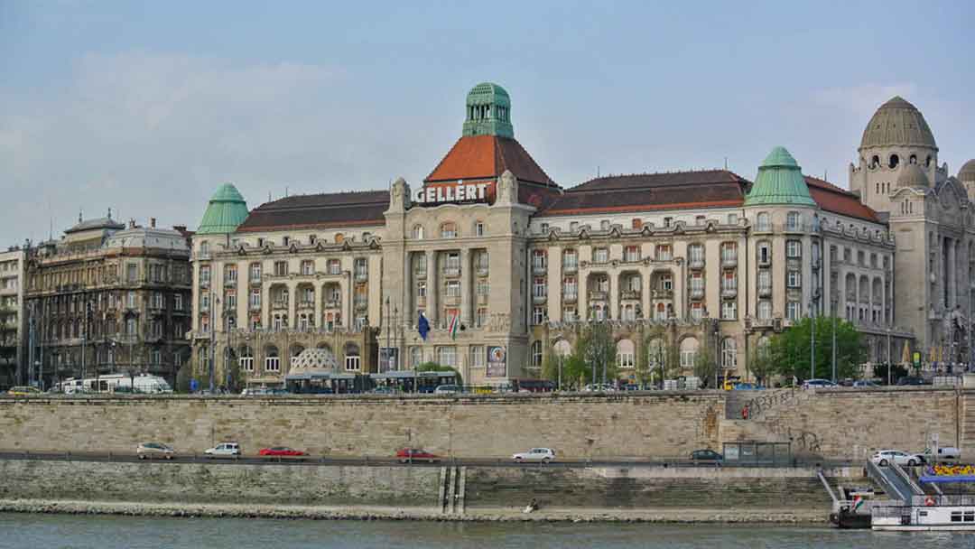 Large square stone building with red roof and Gellert sign on front.