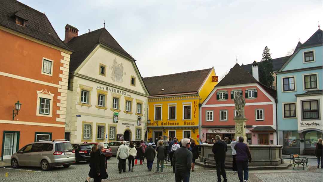 old town square with multiple buildings painted a variety of colors. buildings are from the 15th century.