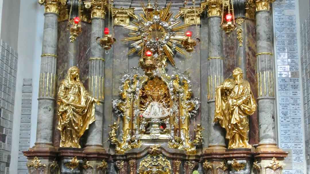 Elaborately decorated altar with gold statues on each side, gold star-like medallion over head and in the center a doll representing the infant Jesus