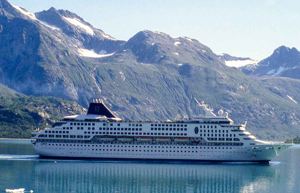 Cruise ship sailing in front of snow topped mountains