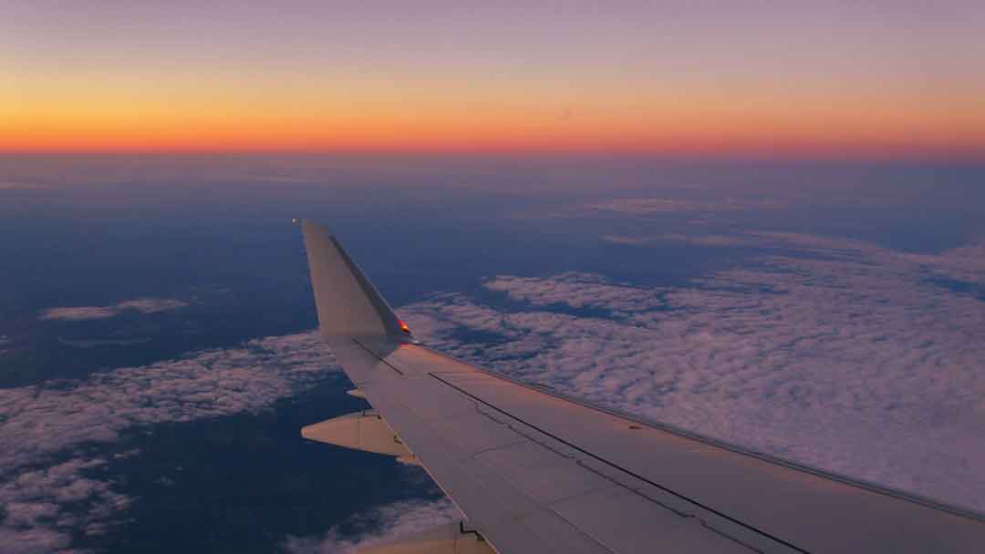Photo of wing of plane on flight at sunset