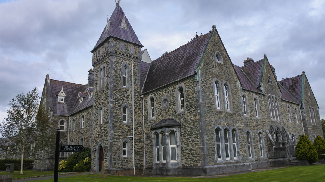 A large gray stone church with many large windows.