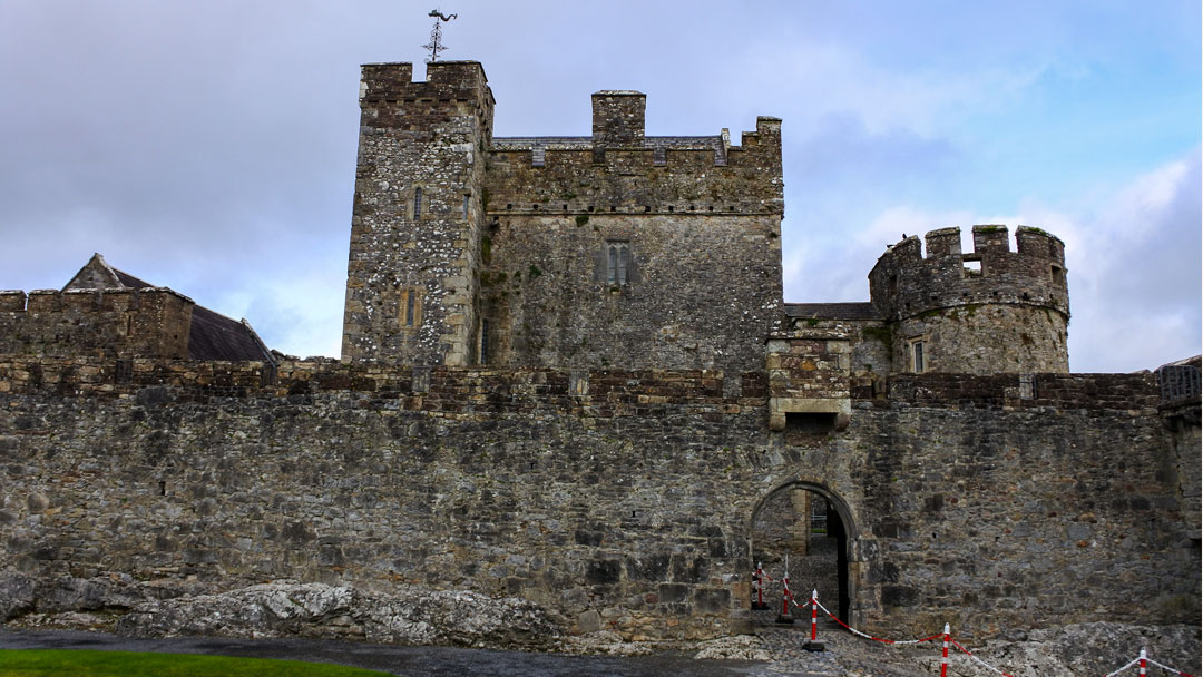 Outside view of the large dark gray stoned walls and facade of Cahir Castle.