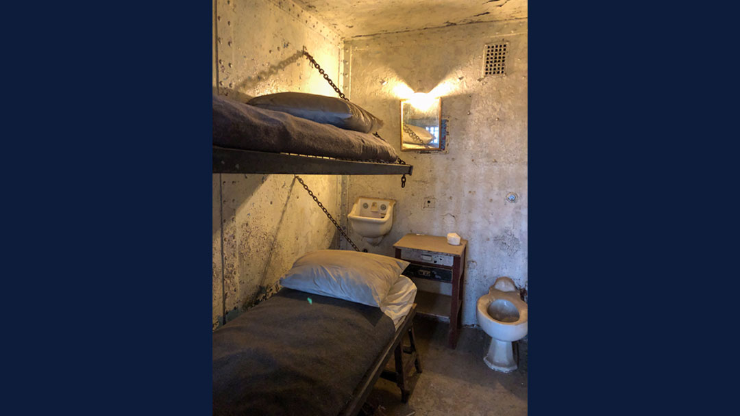 recreated cell within the Ohio State Reformatory shows two made up bunk beds, a small sink, small wooden shelf and exposed toilet.
