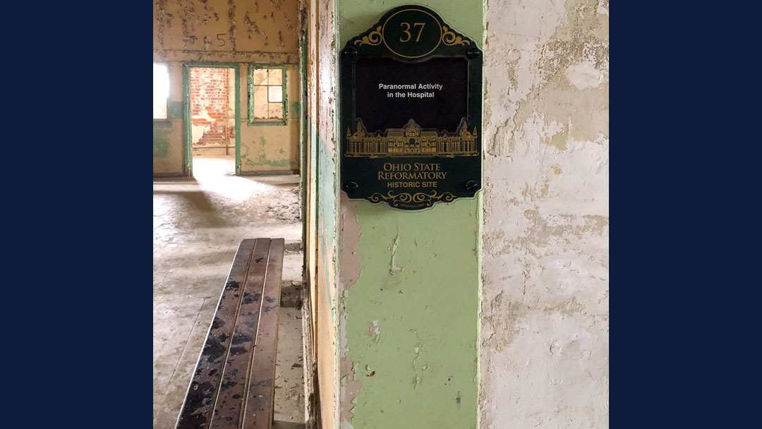 photo of plaque in the hospital area of the Ohio State Reformatory. Plaque states there is a lot of paranormal activity in the Hospital. Paint is peeling off the walls.